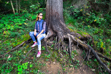 Naklejka na ściany i meble Woman traveler sitting under a big tree in the highlands