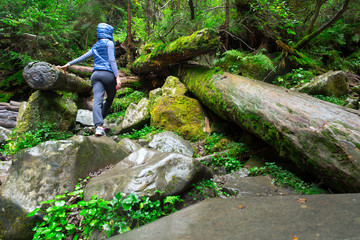 Girl climbs the mountain through the dense forest