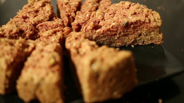 Girl's hand takes a piece of oat cake from black plate on a black table.