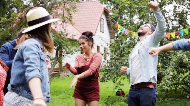 happy friends dancing at summer party in garden