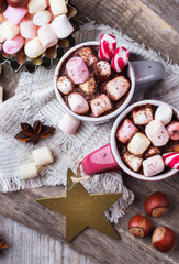 Hot chocolate with marshmallows and spices on rustic wooden table