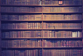 Vintage toned old books on wooden shelves, wisdom concept background.