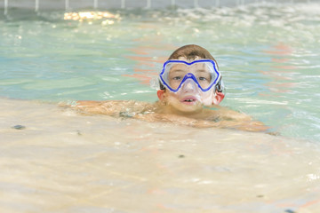 Naklejka premium young happy smiling boy swimming in water pool