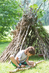 kids playing next to wooden stick house looking like indian hut,