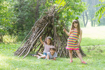 kids playing next to wooden stick house looking like indian hut, © Alena Yakusheva