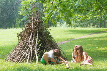 kids playing next to wooden stick house looking like indian hut, © Alena Yakusheva
