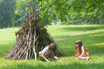 kids playing next to wooden stick house looking like indian hut, © Alena Yakusheva