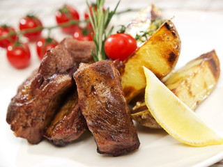 Grilled ribs, French fries and tomato decorated with lemon slice