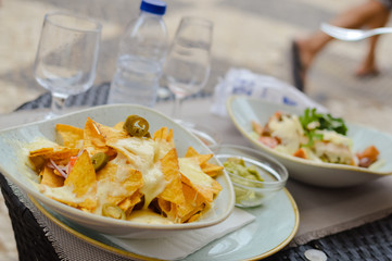 Classical Caesar salad with sliced chiken meat, grilled bacon, lettuce leaves, crackers and cherry tomatoes decorated with basil and parmesan served in white round plate