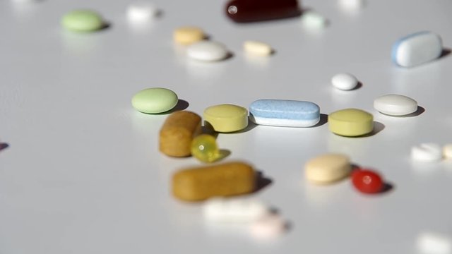 Various types of pills falling on the table
