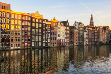 Fototapeta premium Bunte, sich im Wasser spiegelnde Häuserzeile in Amsterdam, Abendsonne