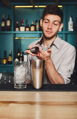 Young handsome barman pouring cocktail drink into glass