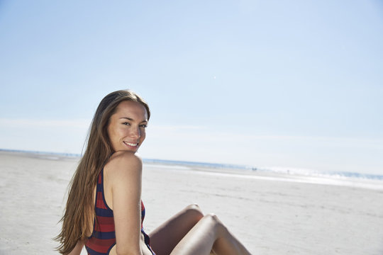Smiling young woman sitting on the beach