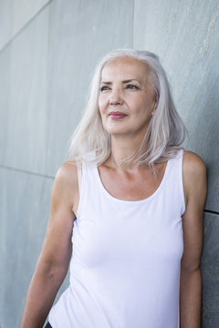 Portrait of woman leaning against wall looking at distance