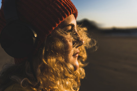 Teenage girl wearing beanie and headphones sitting on the beach