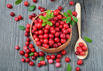 Cowberry in wooden bowl on rustic surface