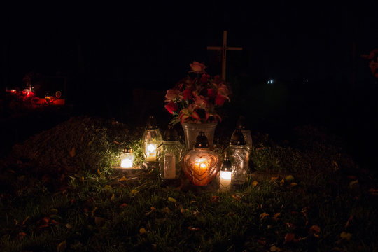Votive candles lantern burning on the graves in Slovak cemetery at night time. All Saints' Day. Solemnity of All Saints. All Hallows eve. 1st November. Feast of All Saints. Hallowmas. All Souls' Day