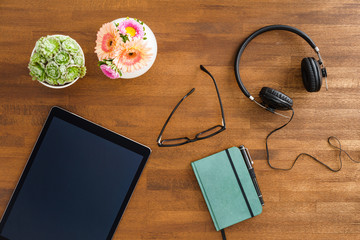 Desktop scene with tablet device, headphones and notebook shot from above