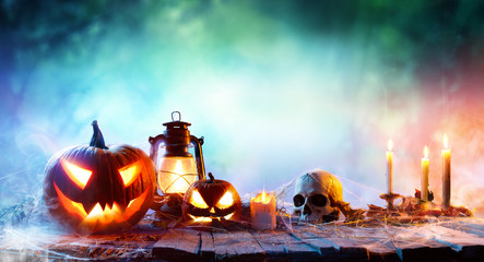 Naklejka premium Halloween - Lanterns And Pumpkins On Wooden Table In A Haunted Forest 