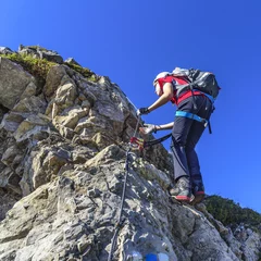 Foto auf Acrylglas Bergsteigen Teenager klettert gut gesichert im Klettersteig