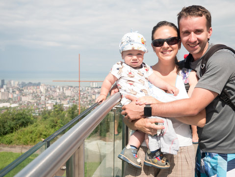 Happy family with a beautiful baby looking at the city from great height of the mountains