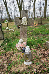 Graves, tombstones and crucifixes on traditional cemetery. Votive candles lantern and flowers on tomb stones in graveyard. All Saints' Day.All Souls' Day. Gravestones in village Tvrdomestice, Slovakia