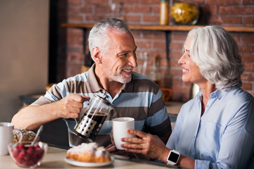 Grandparents drinking and pouring coffee at kitchen