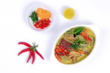 Green chicken curry in coconut milk s with side dish as minced dried shrimp,sliced red chili,sliced kaffir lime leaves and green lemon on white background.