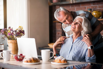 Nice looking old man embracing his wife from her back