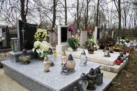 Graves, tombstones and crucifixes on traditional cemetery. Votive candles lantern and flowers on tomb stones in graveyard. All Saints' Day.All Souls' Day. Gravestones in village Tvrdomestice, Slovakia