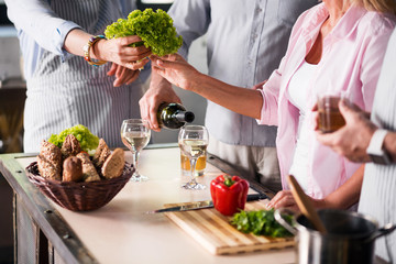 Family cooking food together while enjoying wine