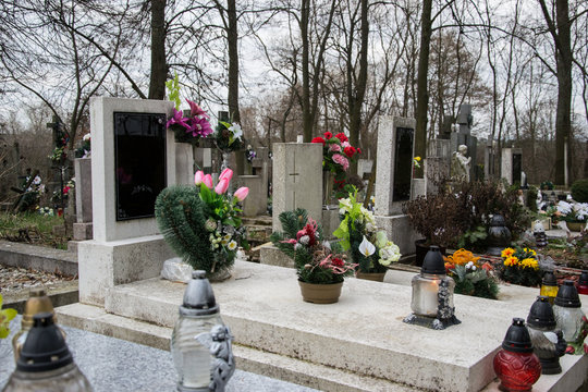 Graves, tombstones and crucifixes on traditional cemetery. Votive candles lantern and flowers on tomb stones in graveyard. All Saints' Day.All Souls' Day. Gravestones in village Tvrdomestice, Slovakia