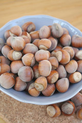 nocciole intere in ciotola grigia su tavolo di legno