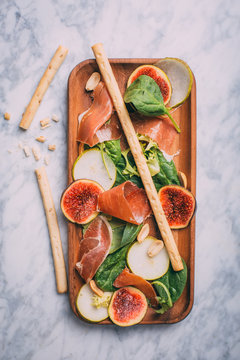 Healthy salad with lettuce, figs, prosciutto and pear