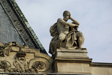 Fototapeta na wymiar Statue d'homme sur les toits du Louvre à Paris, France