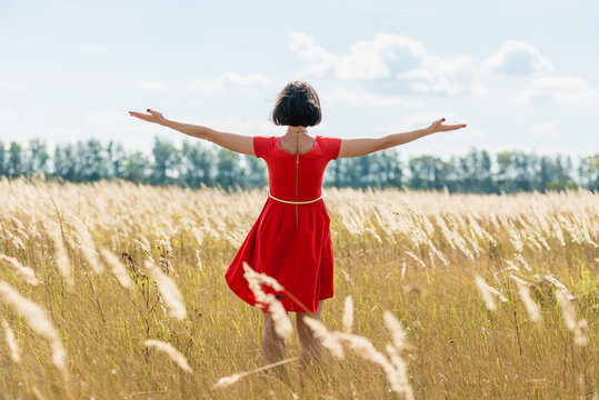 girl in red dress walking on the field