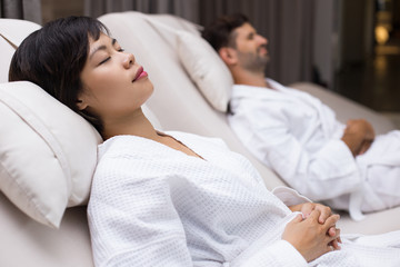 Dozing woman and man lying on deckchairs in spa