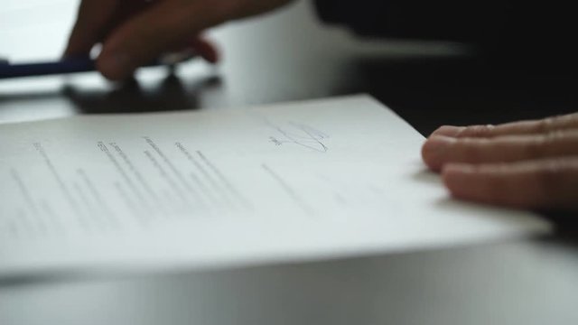 businessman signs a contract on a wooden table