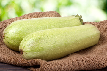 two courgettes on sackcloth with a blurred background