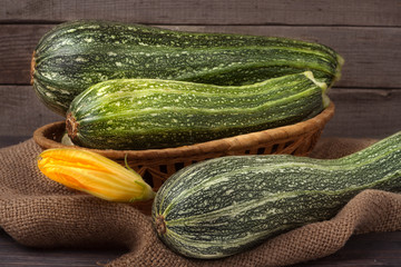 green zucchini and courgettes with a flower on sackcloth wooden background