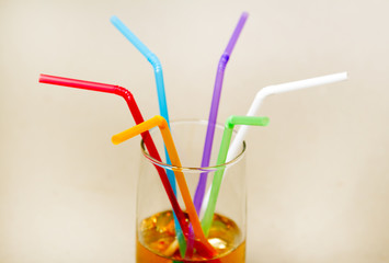 Multicolored tubes in a glass with a yellow drink
