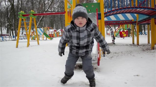 slides down the playground in winter/Winter entertainment in the playground boy down the slide