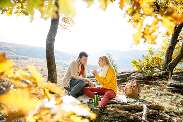 Beautiful couple in autumn forest eating and drinking