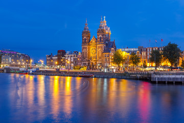 Night panoramic city view of Amsterdam canal, bridge and Basilica of Saint Nicholas, Holland, Netherlands. Long exposure.