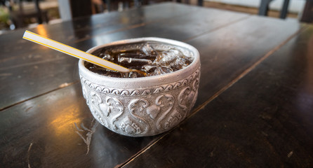 Water bowl cola with ice on wood table on a hot day of Summer