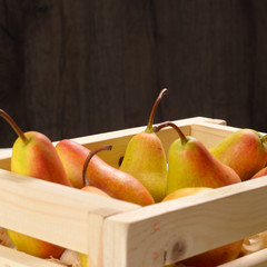 Wooden crate with pears on white table