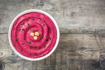 Beet hummus in bowl  on wooden table background

