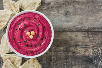 Beet hummus in bowl  on wooden table background


