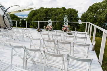 White chairs stand in the front of a wedding altar made of cryst