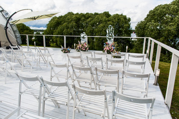 White chairs stand in the front of a wedding altar made of cryst